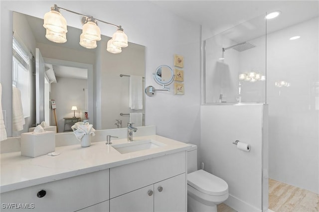 bathroom featuring toilet, a walk in shower, wood finished floors, and vanity