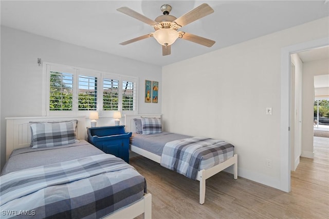 bedroom with ceiling fan, wood finished floors, and baseboards