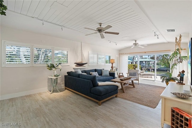 living area featuring visible vents, baseboards, rail lighting, vaulted ceiling, and light wood-style floors