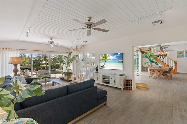 living room with track lighting, visible vents, wood finished floors, vaulted ceiling, and a notable chandelier