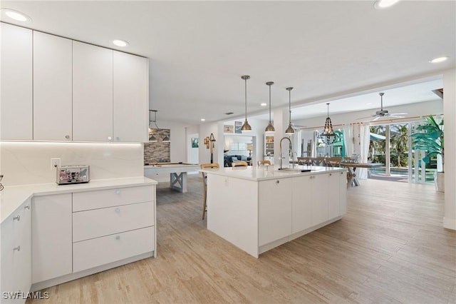 kitchen featuring white cabinetry, open floor plan, light countertops, modern cabinets, and decorative light fixtures