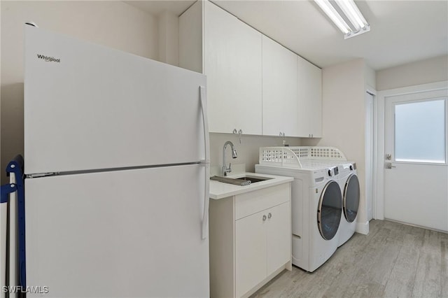 laundry room with cabinet space, a sink, washer and dryer, and light wood-style floors