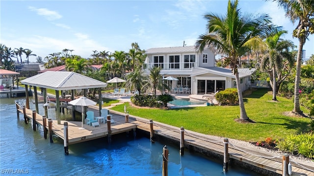 dock area featuring boat lift, a water view, a yard, an outdoor pool, and a patio area