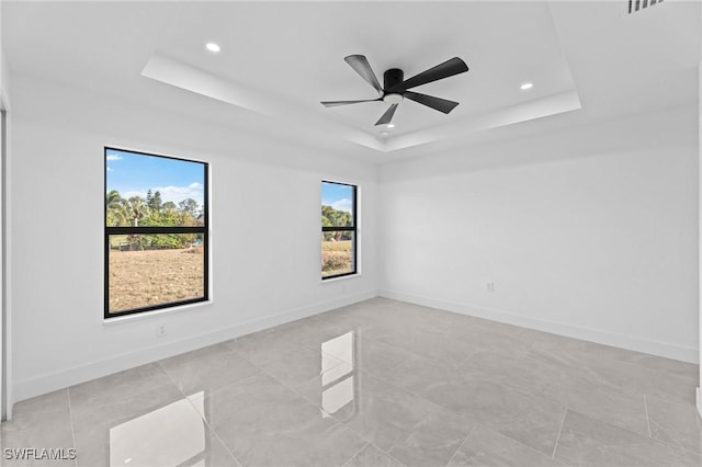 unfurnished room with ceiling fan and a tray ceiling