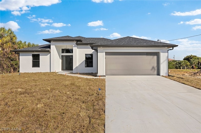 prairie-style house featuring a garage and a front yard