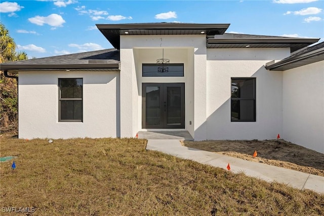 property entrance with a lawn and french doors