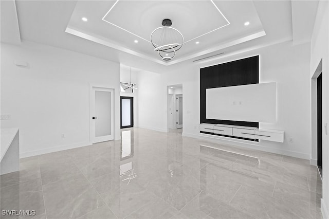 unfurnished living room featuring a towering ceiling, a tray ceiling, and a notable chandelier