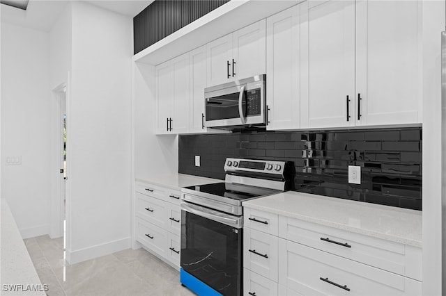 kitchen featuring stainless steel appliances, white cabinetry, backsplash, and light stone counters