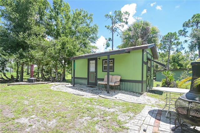 back of property with a lawn and an outdoor fire pit