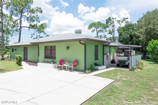 back of property with a carport and a yard