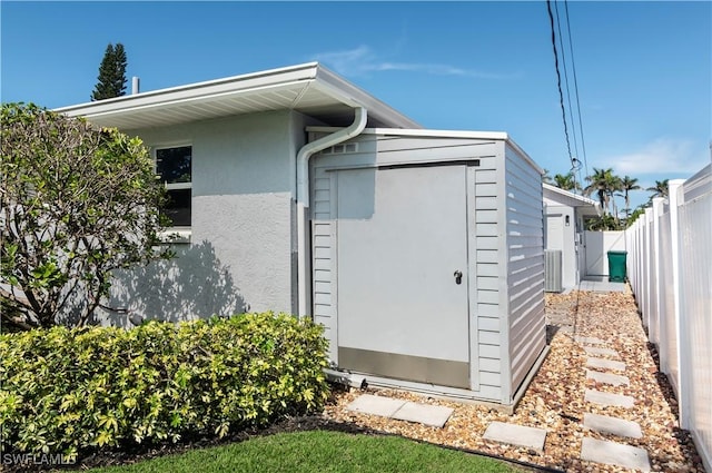 view of property exterior featuring central AC and a storage shed