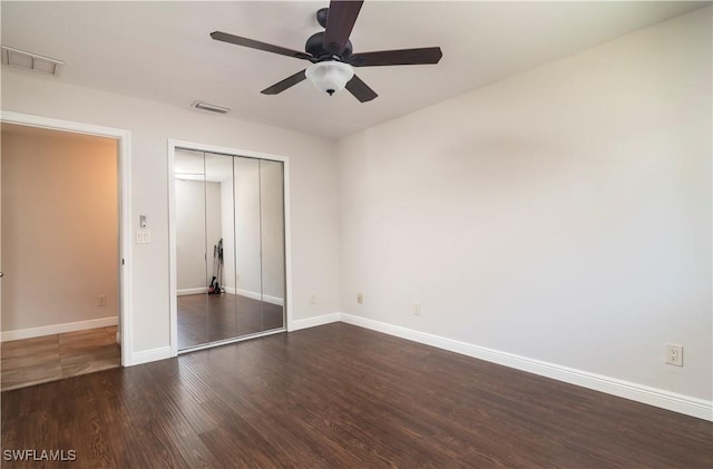 unfurnished bedroom featuring ceiling fan, dark hardwood / wood-style flooring, and a closet