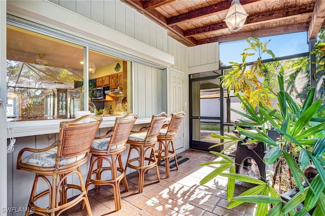 sunroom with beam ceiling, plenty of natural light, wooden ceiling, and indoor bar