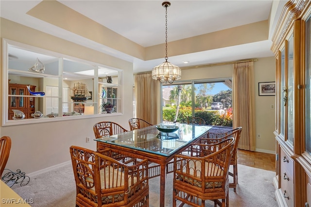 dining area with a raised ceiling, light parquet flooring, and a notable chandelier