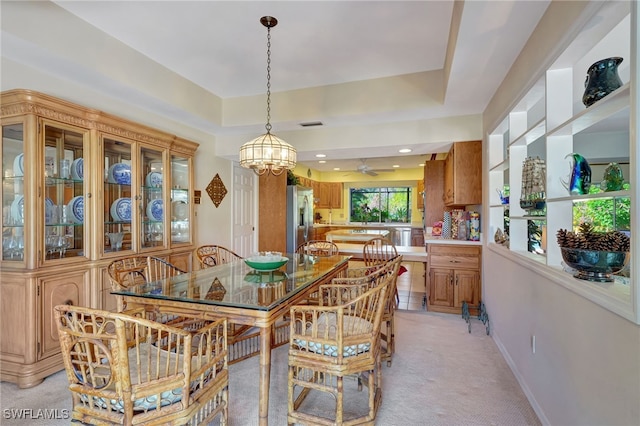 dining space with ceiling fan with notable chandelier and light colored carpet