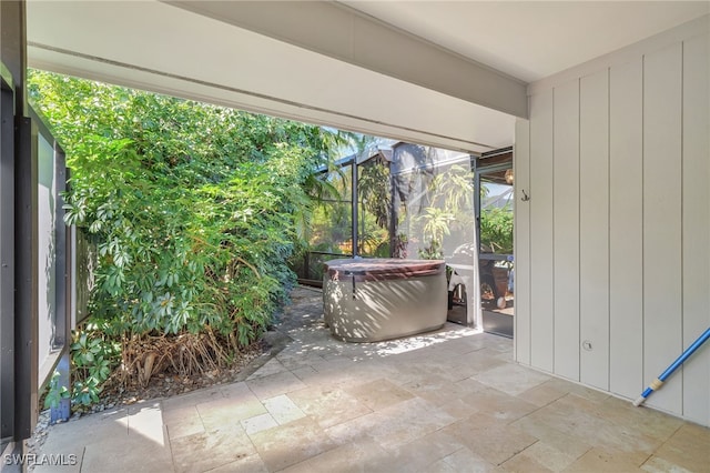 view of patio / terrace with a hot tub and glass enclosure