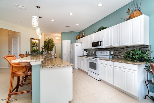 kitchen featuring pendant lighting, white appliances, backsplash, white cabinets, and a kitchen bar