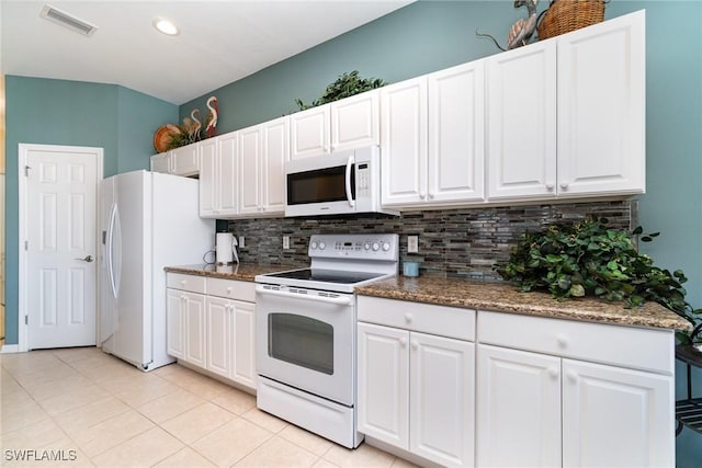 kitchen with white cabinetry, dark stone countertops, light tile patterned floors, white appliances, and decorative backsplash