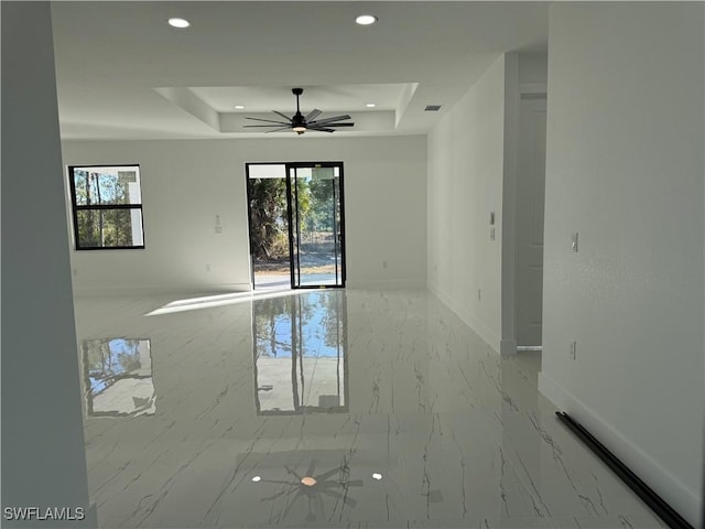 spare room featuring a wealth of natural light, ceiling fan, and a tray ceiling