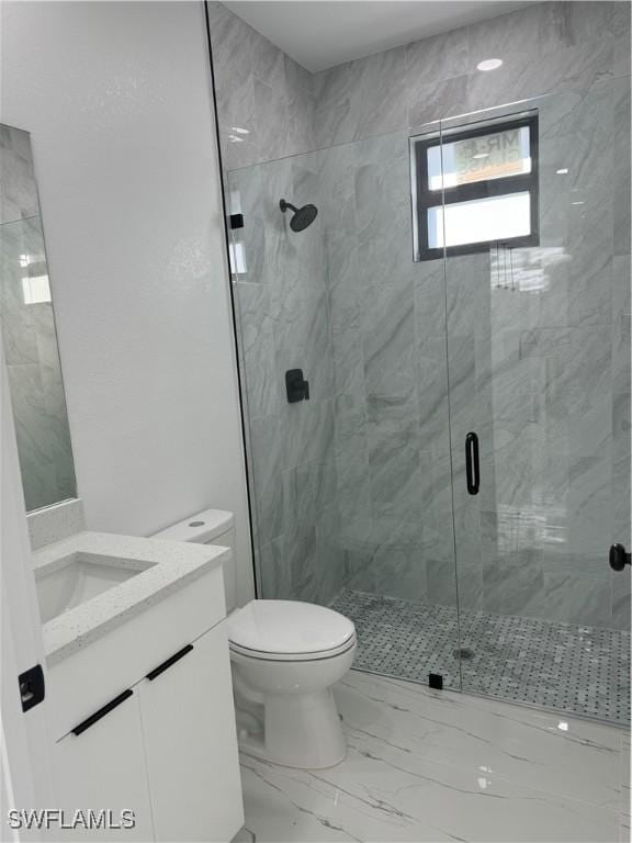 bathroom featuring vanity, a shower with shower door, and toilet