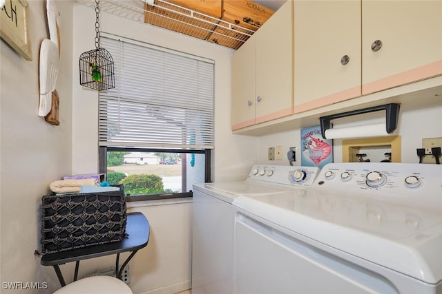 clothes washing area with cabinets and washing machine and dryer