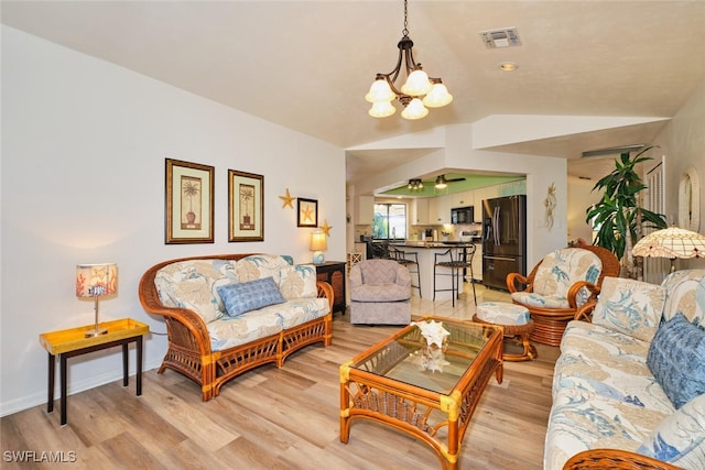 living room with lofted ceiling, a chandelier, and light hardwood / wood-style flooring