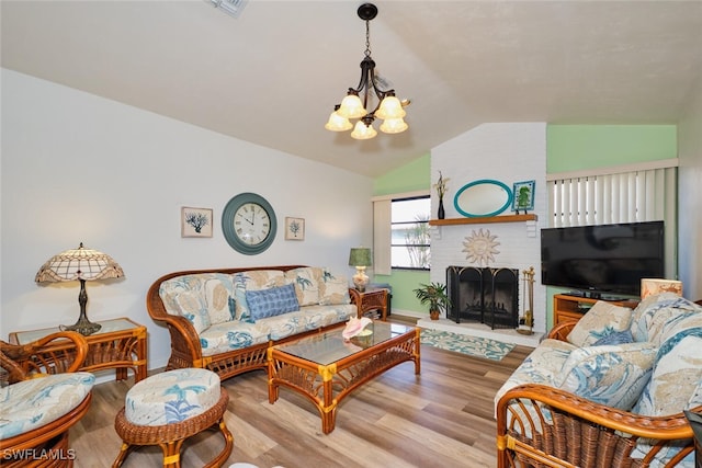 living room featuring lofted ceiling, a fireplace, light hardwood / wood-style floors, and a chandelier