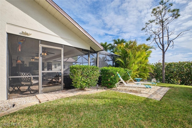 view of yard featuring a patio, ceiling fan, and glass enclosure