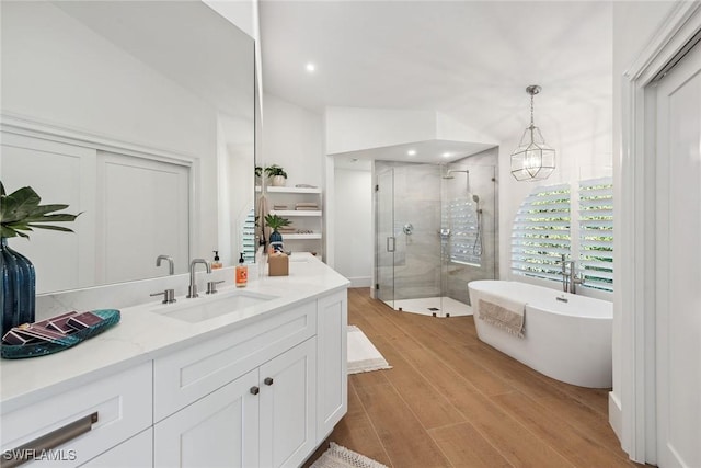 full bathroom with recessed lighting, wood finished floors, vanity, a freestanding bath, and a stall shower