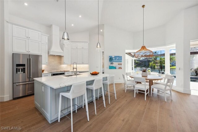 kitchen with pendant lighting, premium range hood, high end refrigerator, and white cabinets