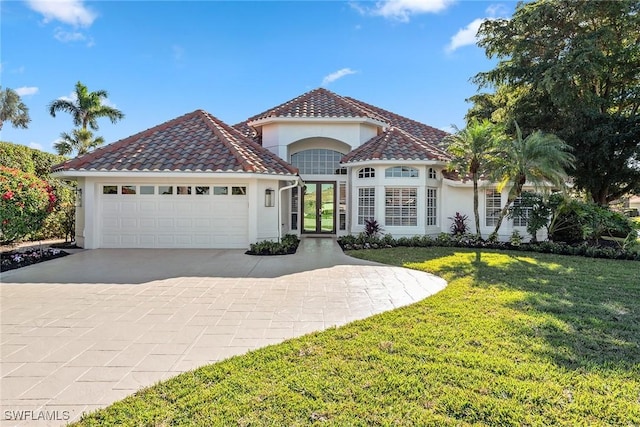 mediterranean / spanish-style home with a garage, concrete driveway, a tiled roof, stucco siding, and a front lawn