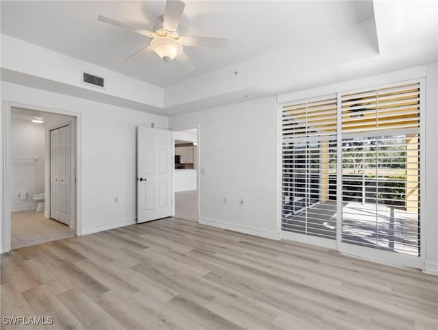 spare room featuring a tray ceiling, ceiling fan, and light hardwood / wood-style floors