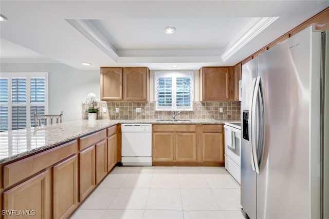 kitchen featuring a raised ceiling, white appliances, and decorative backsplash