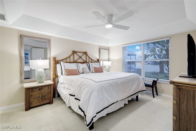 carpeted bedroom featuring ceiling fan and a tray ceiling