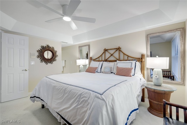 bedroom featuring ceiling fan, a tray ceiling, and light colored carpet