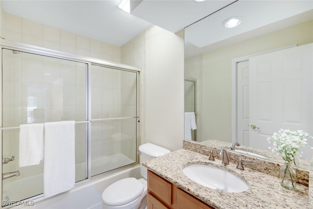 full bathroom with vanity, bath / shower combo with glass door, and toilet