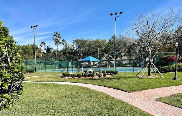 view of home's community with tennis court and a lawn