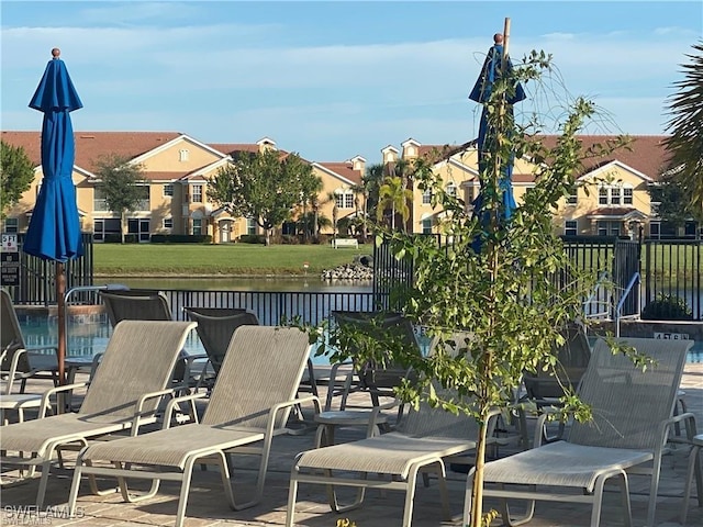 view of patio with fence and a water view