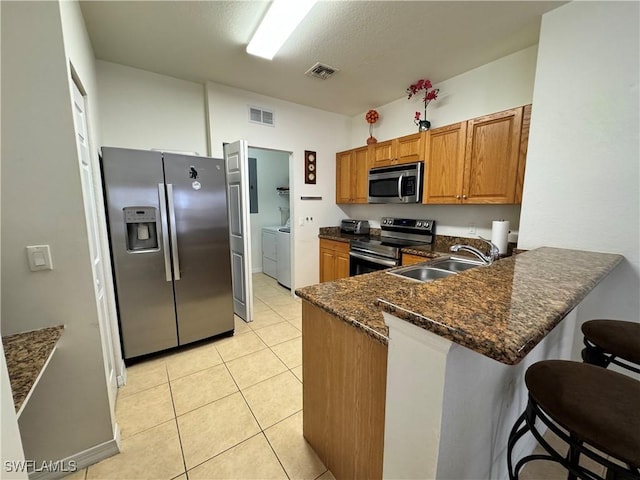 kitchen with a sink, visible vents, washer and clothes dryer, and appliances with stainless steel finishes