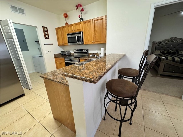 kitchen featuring visible vents, light tile patterned floors, a sink, appliances with stainless steel finishes, and a kitchen bar