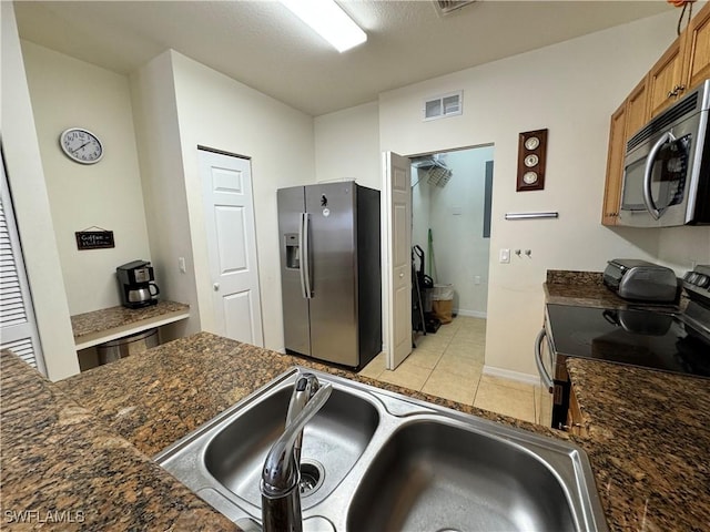 kitchen featuring baseboards, visible vents, brown cabinetry, stainless steel appliances, and a sink