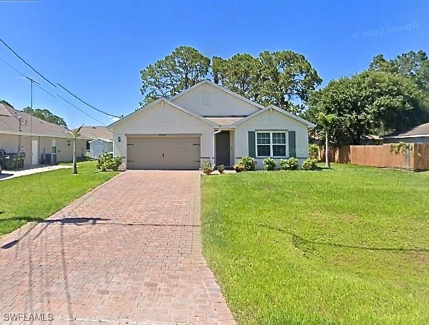 ranch-style house featuring cooling unit, a garage, and a front lawn