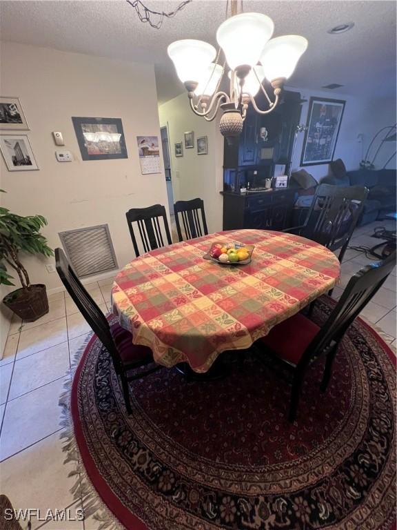 dining area featuring a chandelier, a textured ceiling, and light tile patterned floors