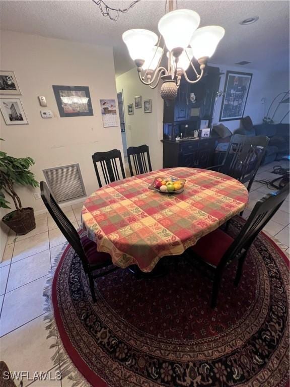 tiled dining room featuring a textured ceiling and a notable chandelier