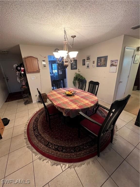 tiled dining area featuring a notable chandelier and a textured ceiling