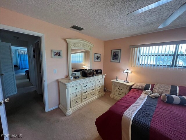 bedroom with a textured ceiling, visible vents, and light carpet
