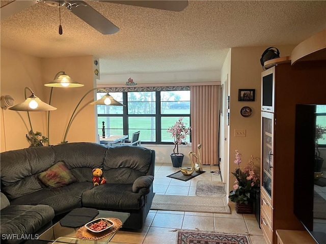 living room featuring a ceiling fan, a textured ceiling, and light tile patterned flooring