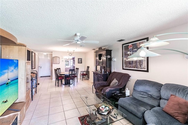 living room featuring a textured ceiling, ceiling fan, light tile patterned floors, and visible vents