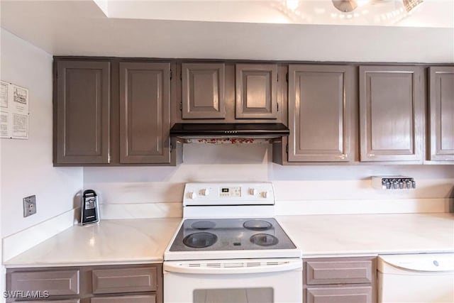 kitchen featuring gray cabinetry, light countertops, under cabinet range hood, and white appliances