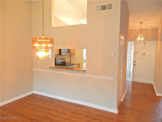 kitchen with a notable chandelier, stainless steel appliances, wood finished floors, visible vents, and baseboards